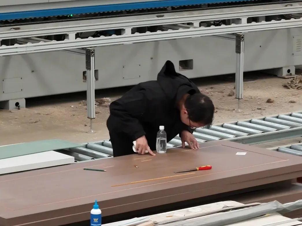 Worker inspecting a finished wooden door panel