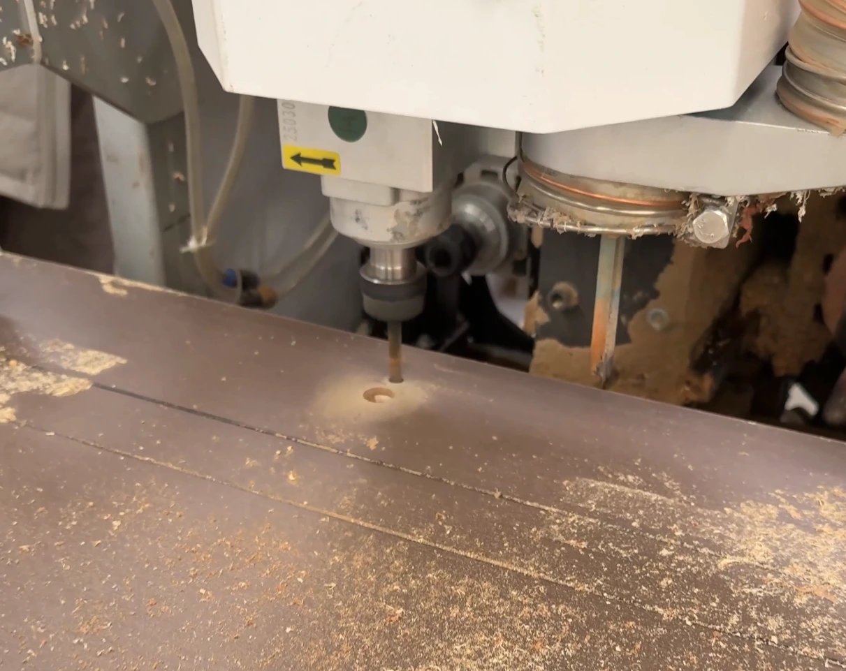 Close-up of a CNC cutter machining a hole in a wooden panel